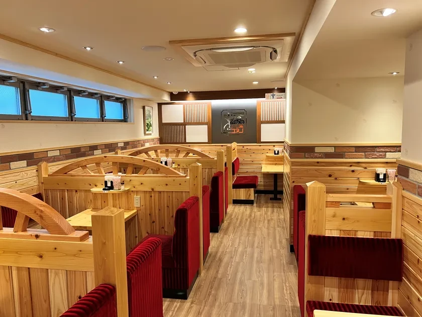 赤いソファ、木の仕切り、レンガ風の壁を備えた板橋仲宿店の公式内観写真。